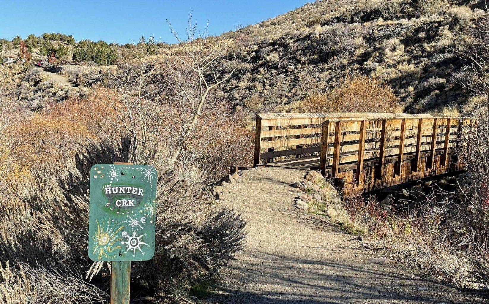 Trail crossing a footbridge into sagebrush hills at Hunter Creek